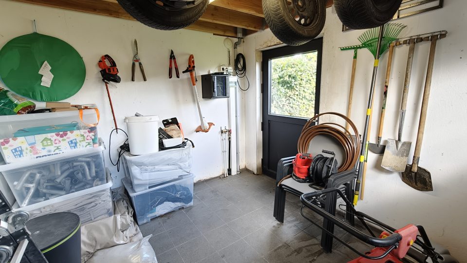Binnenkant van het tuinhuis: betegelde vloer, raam, stopcontacten en bergruimte voor tuingerief en winterbanden